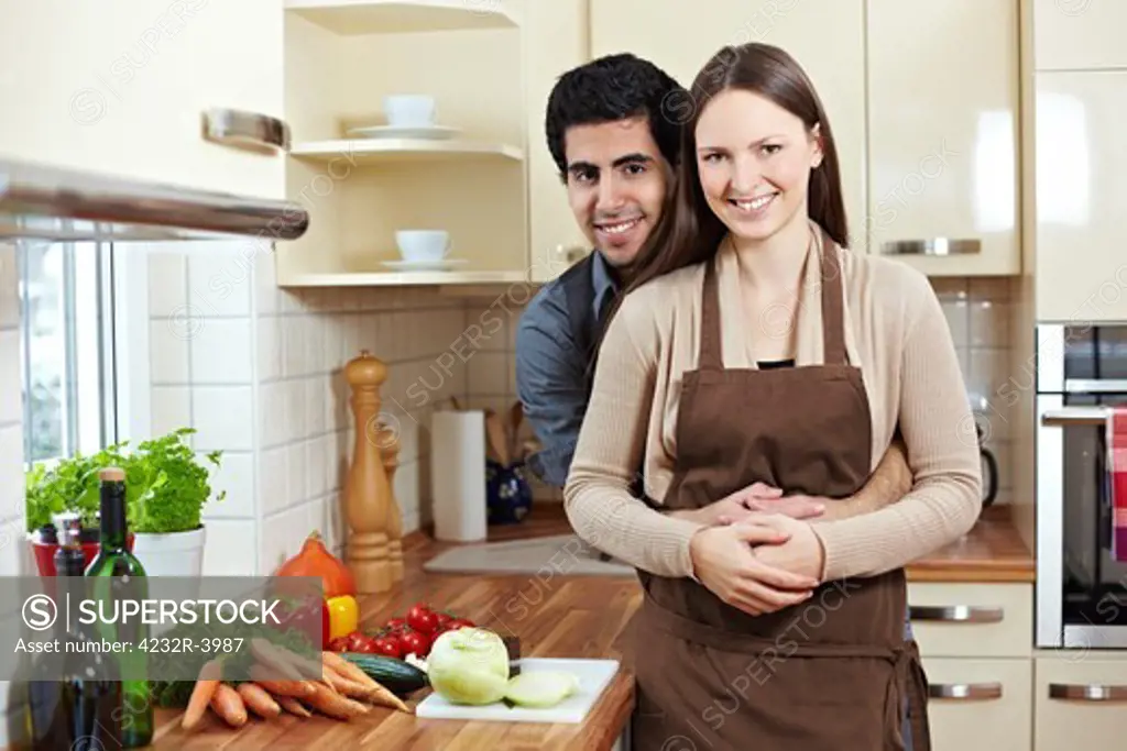 Happy smiling young couple standing in a kitchen