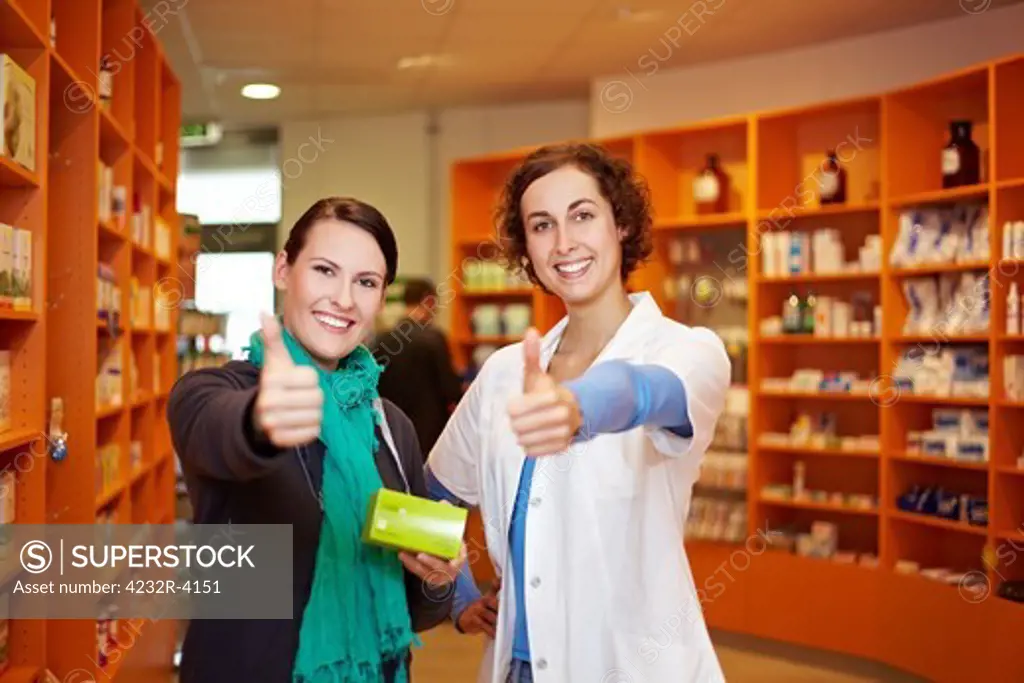 Happy pharmacist and customer holding thumbs up in a pharmacy