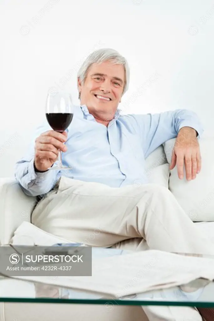 Happy senior man toasting with glass of red wine