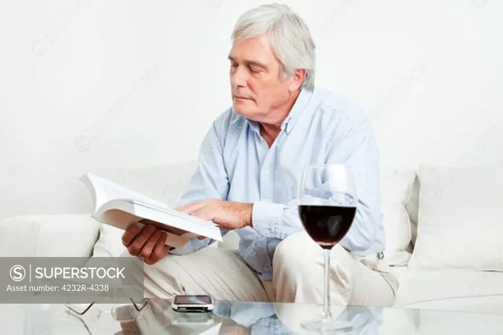 Senior man reading a book on the couch in the living room