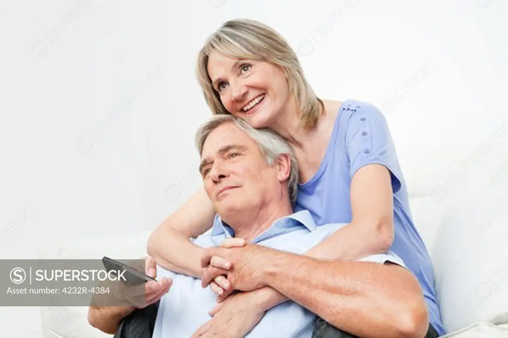 Senior couple watching TV together with remote control at home