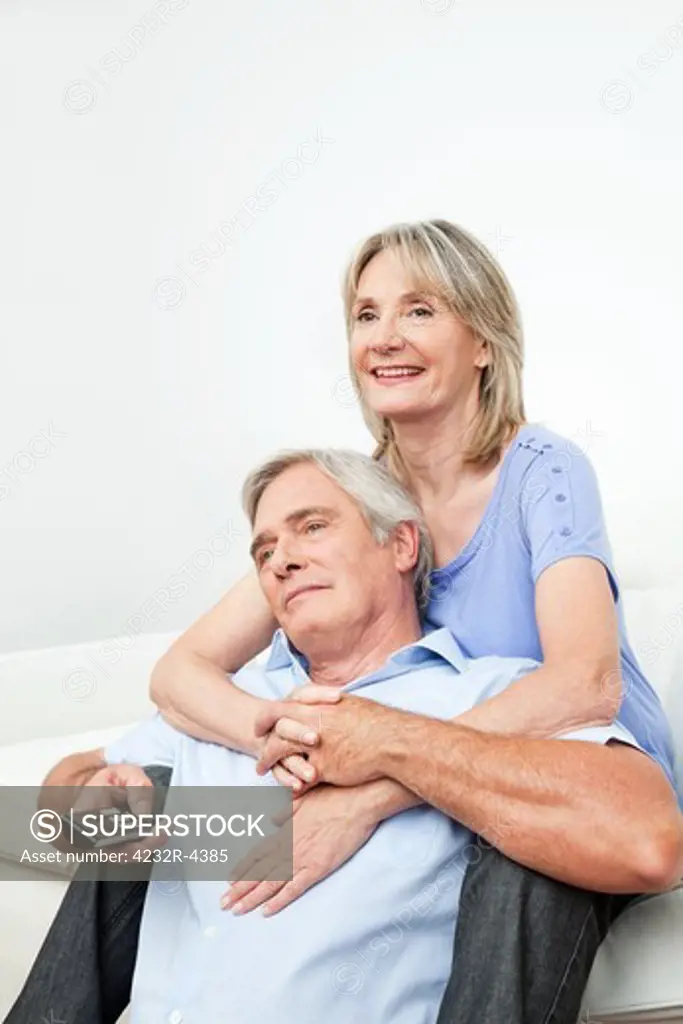 Happy senior couple watching TV at home with remote control