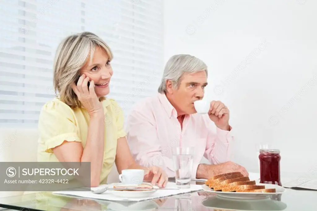 Senior woman using her cell phone at breakfast table