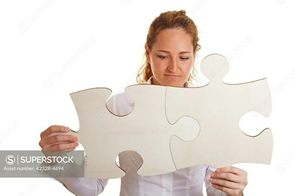 Business woman putting together two oversized jigsaw pieces