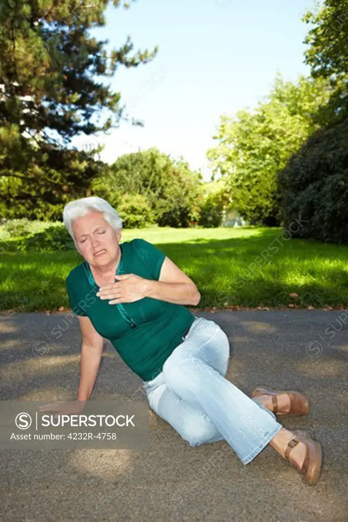 Senior woman with heart pain sitting in a park