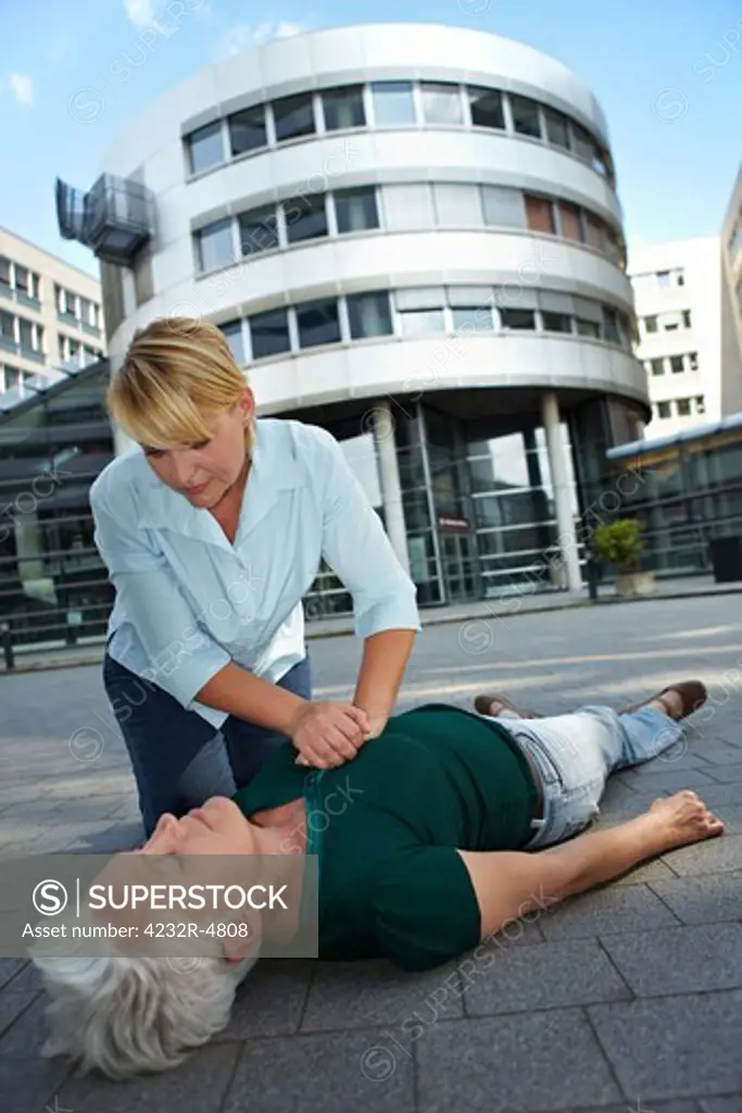 Passerby giving CPR to senior woman as First Aid