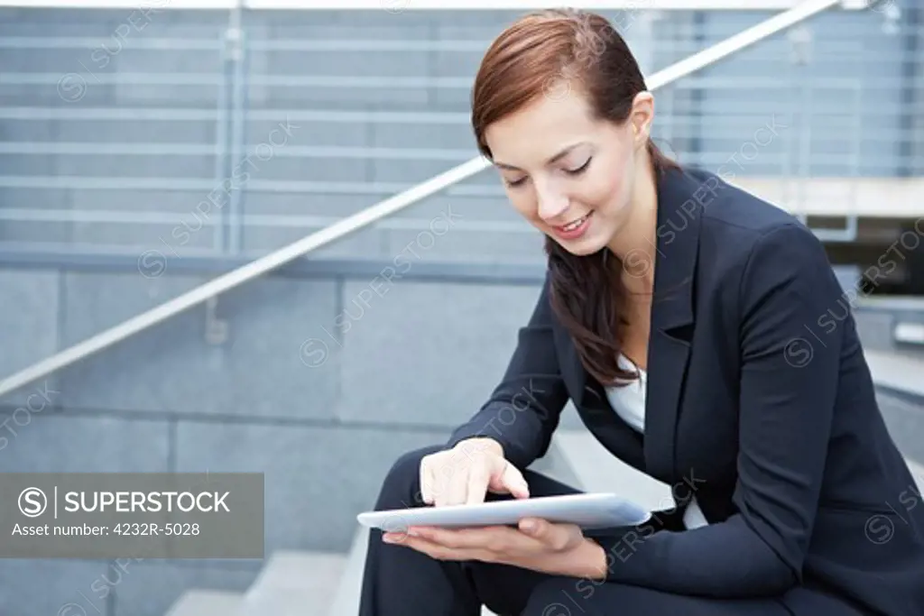 Urban business woman sitting with tablet computer on stairs