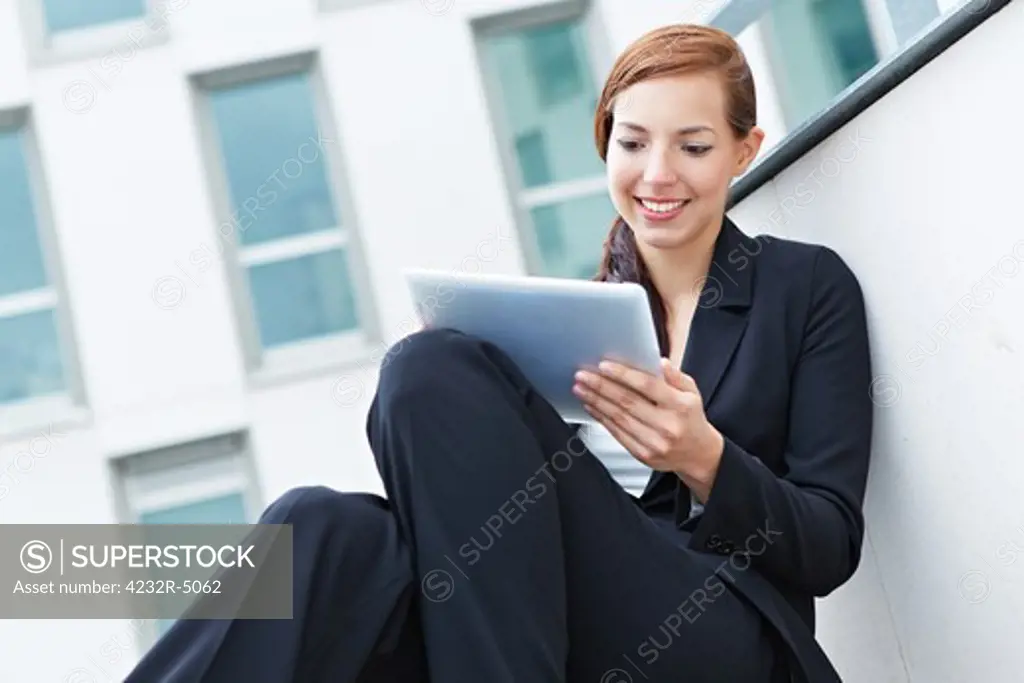 Female student sitting on stairs with a tablet pc