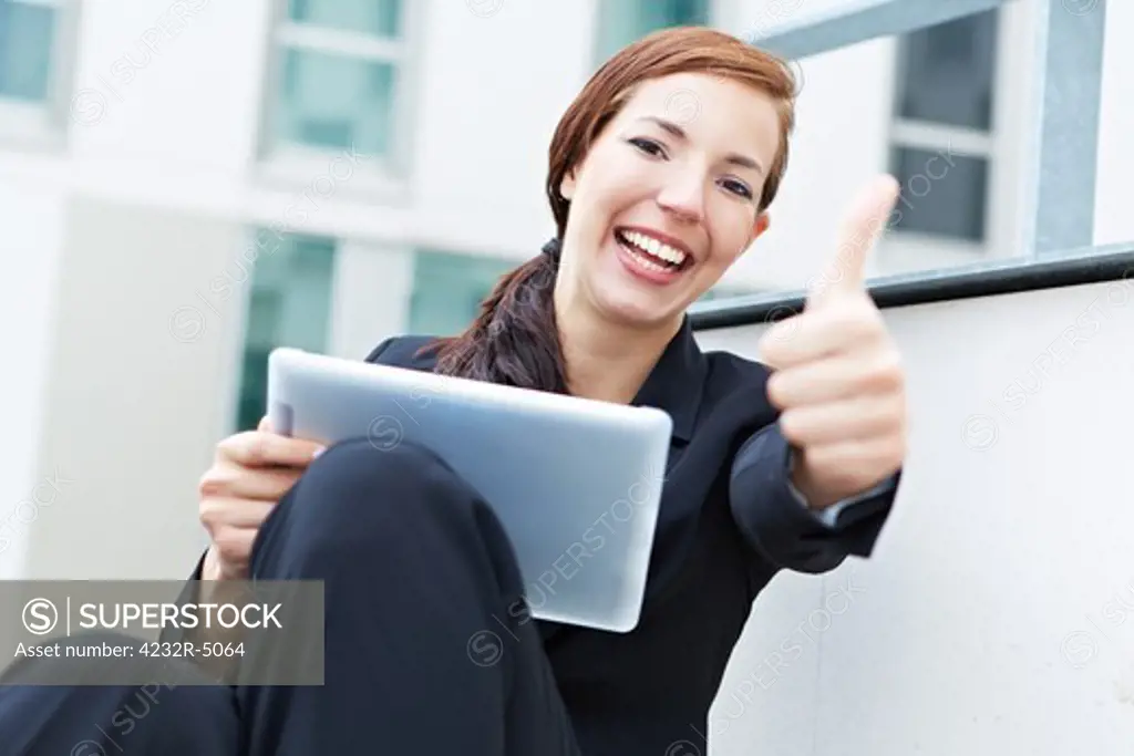 Happy woman with a tablet pc holding her thumbs up