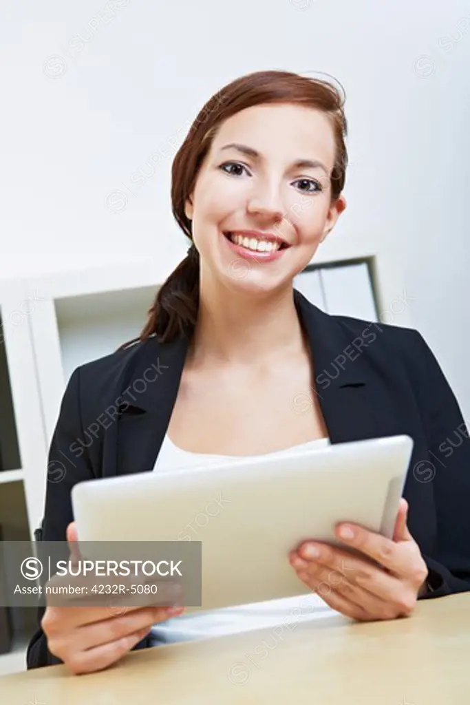 Smiling businesswoman sitting with her tablet pc in an office