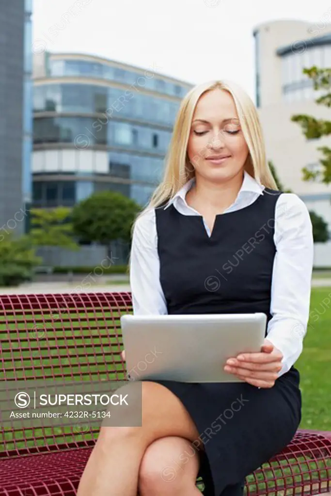 Attractive business woman with tablet computer on a park bench