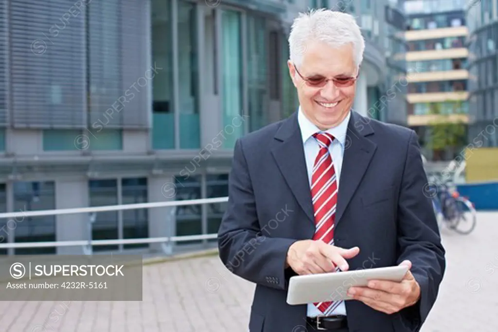Elderly smiling business man looking at tablet PC in his hand