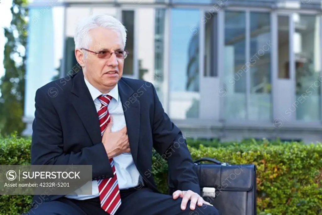 Senior business man with aching heart holding his chest