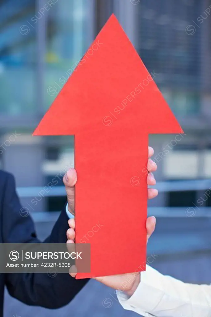 Hands holding a red arrow pointing up
