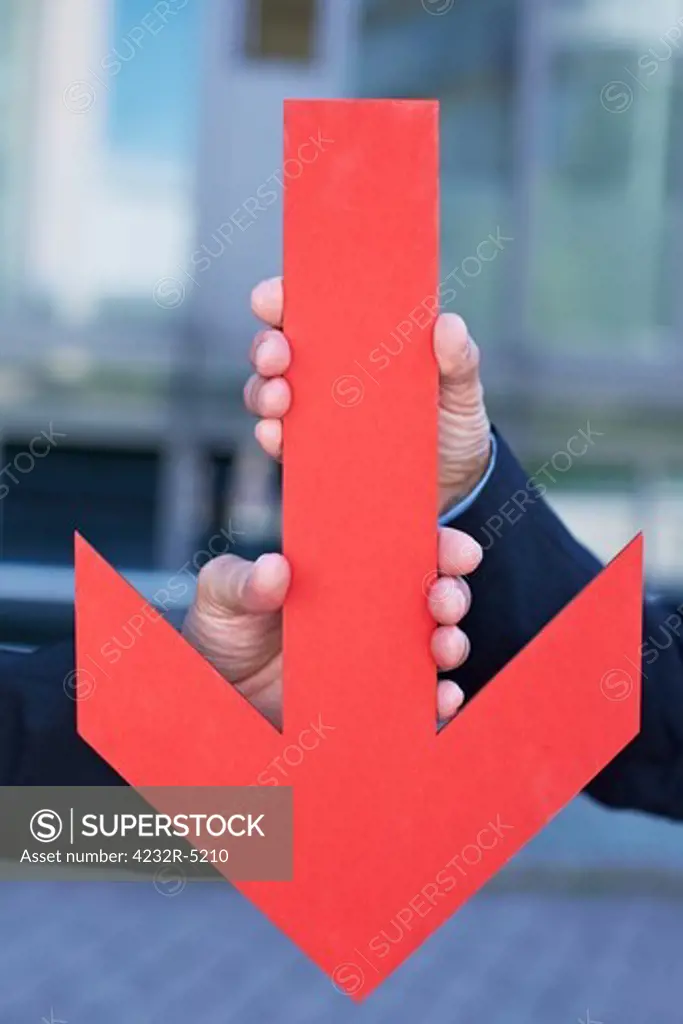 Two business hands holding a red arrow pointing down
