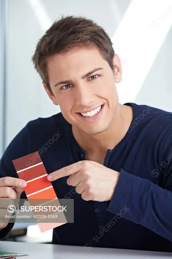 Smiling graphic designer with red color samples in his office