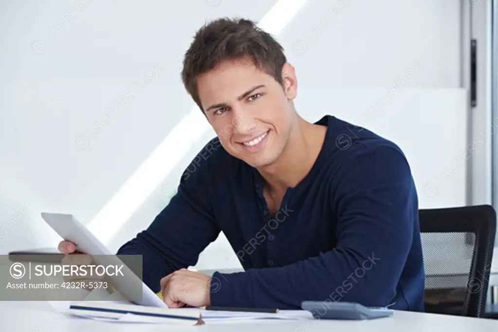 Happy designer sitting at his desk with a tablet computer in his hand