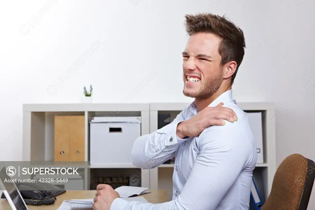 Business man with shoulder pain in office at desk