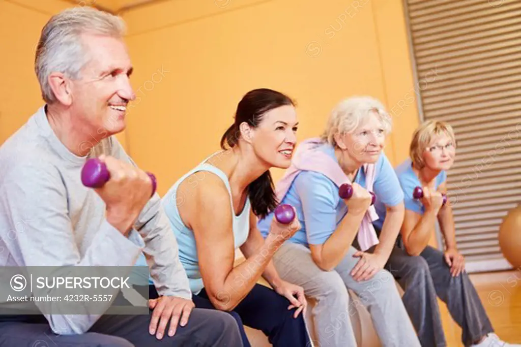 Senior group exercising with dumbbells in a health club