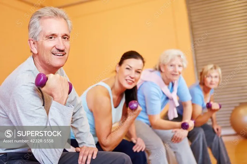 Elderly group doing senior sports with dumbbells in fitness center