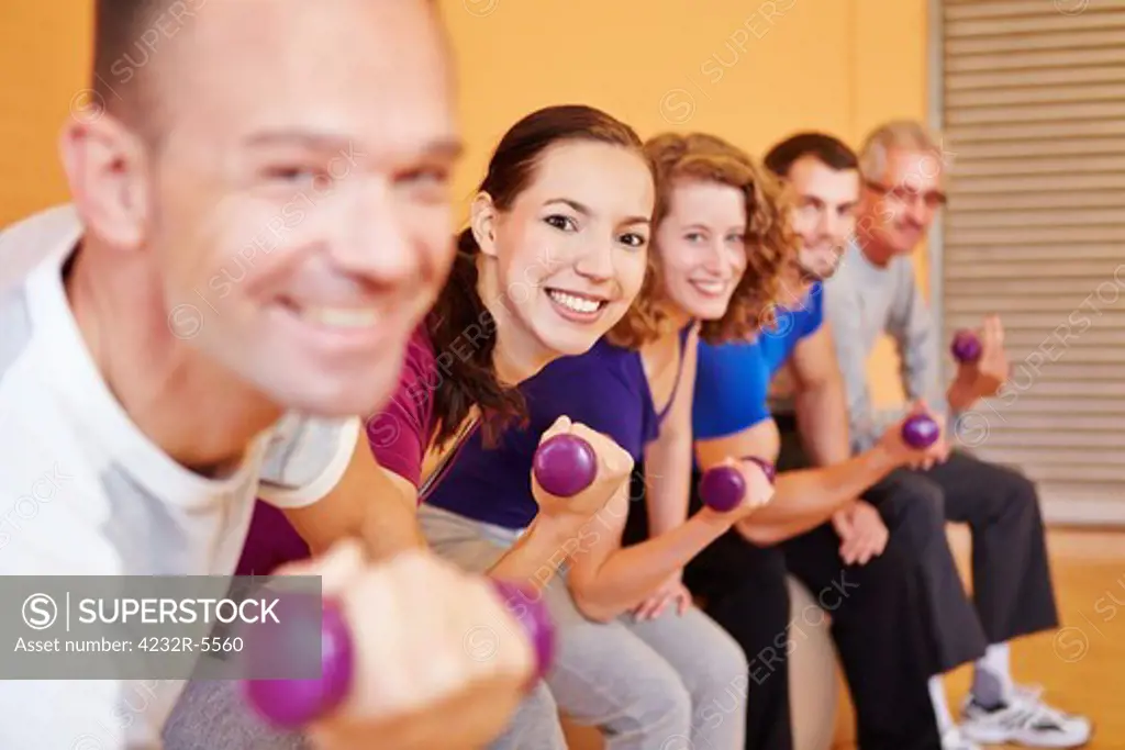 Happy group lifting dumbbells in a fitness center gym