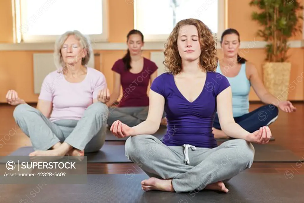 Group of women doing relaxing yoga exercises in gym