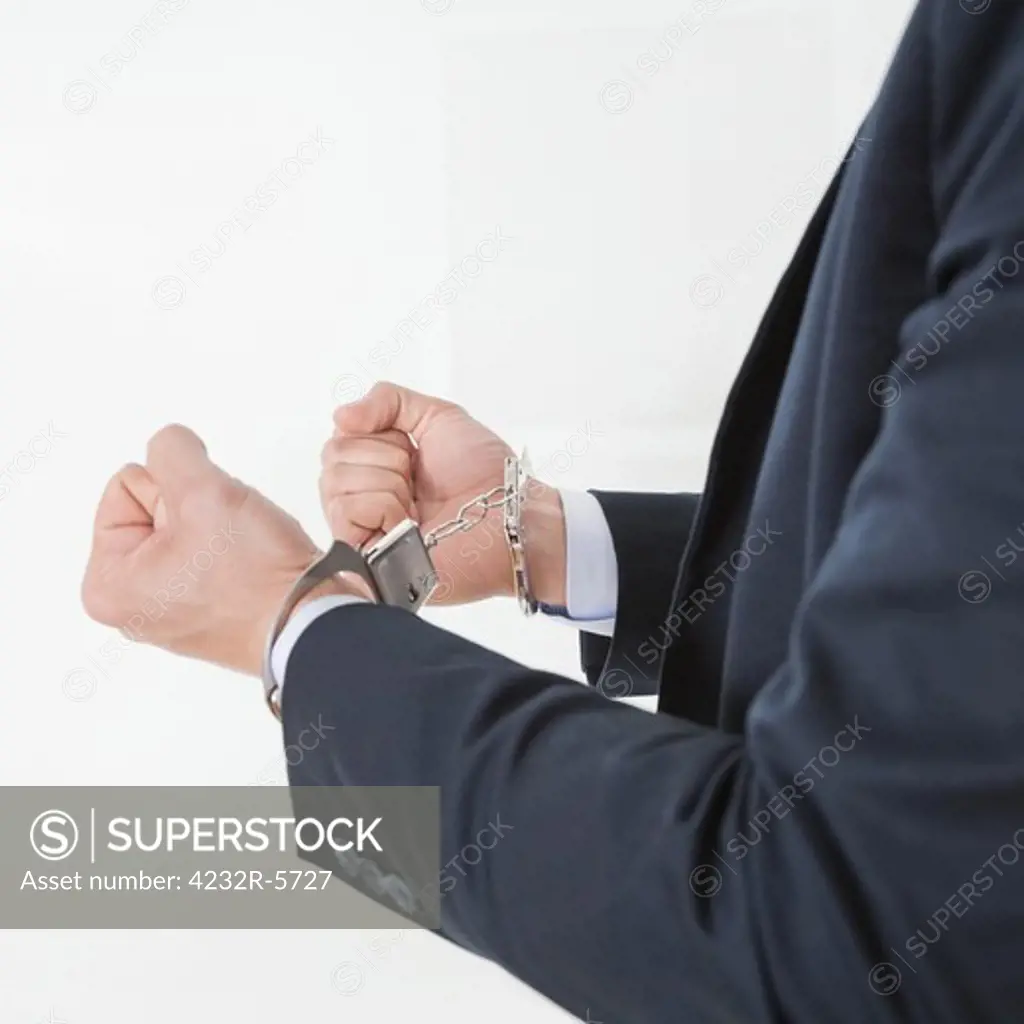 Businessman in handcuffs getting arrested for white collar crimes