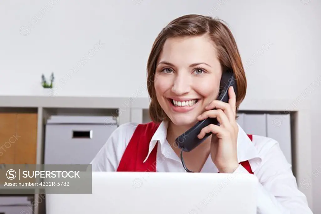 Happy woman in office calling the customer support hotline