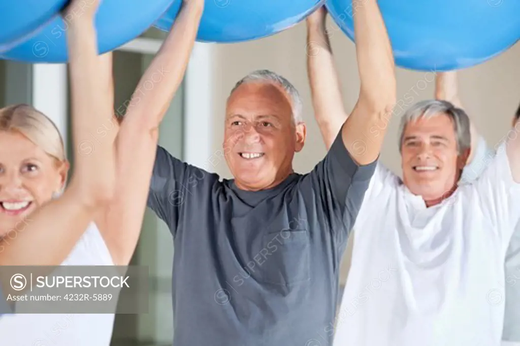 Senior citizens exercising with blue gym balls in fitness center