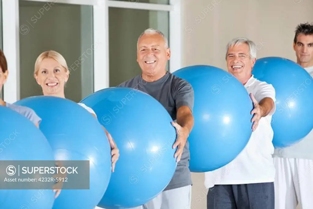 Happy senior group doing fitness exercises with blue gym balls