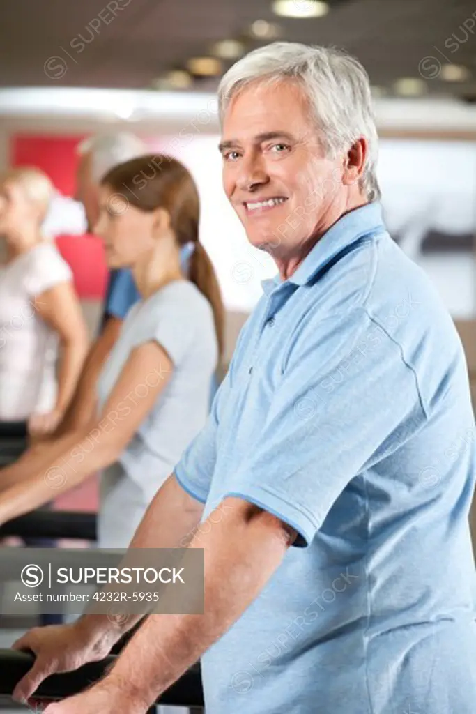 Elderly man exercising on fitness treadmill in gym