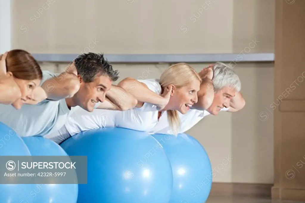 Senior people doing crunches on gym balls in fitness center