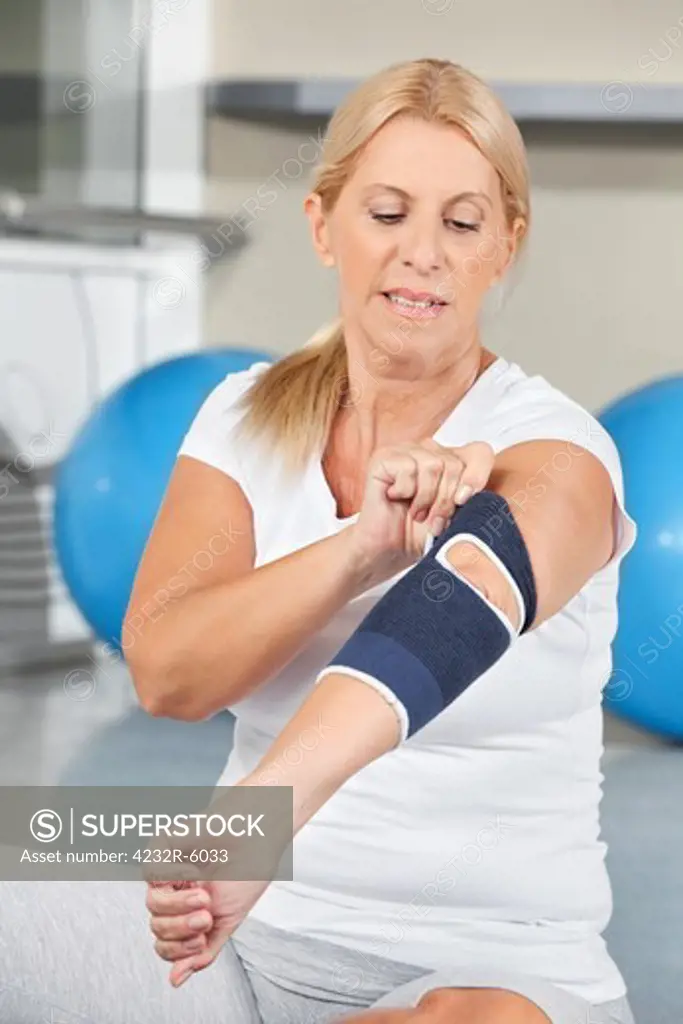 Senior woman with bandage on elbow in fitness center