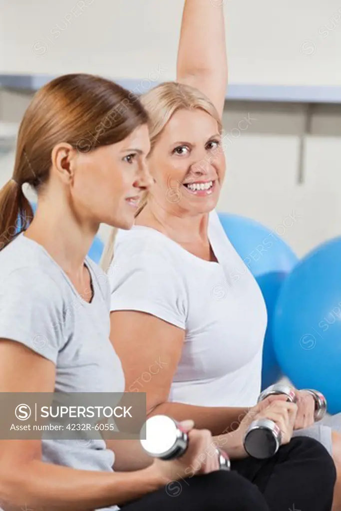 two elderly women working out with dumbbells in gym
