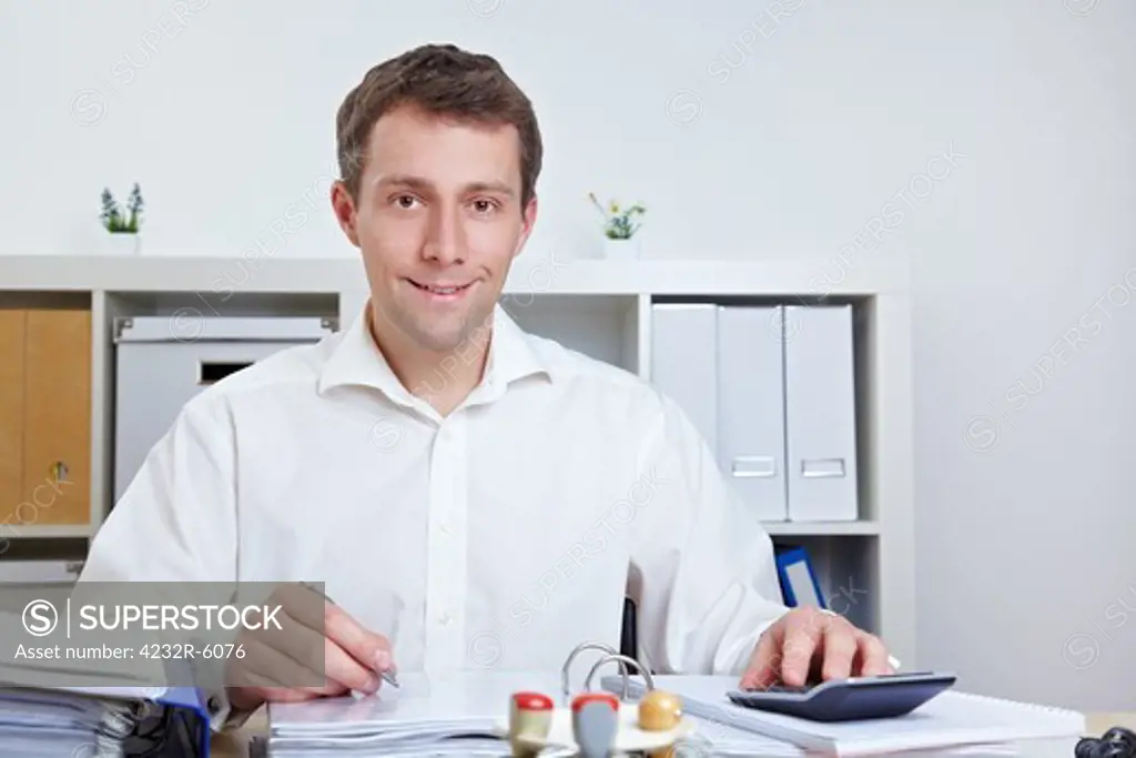 Smiling business man working at his desk in his office
