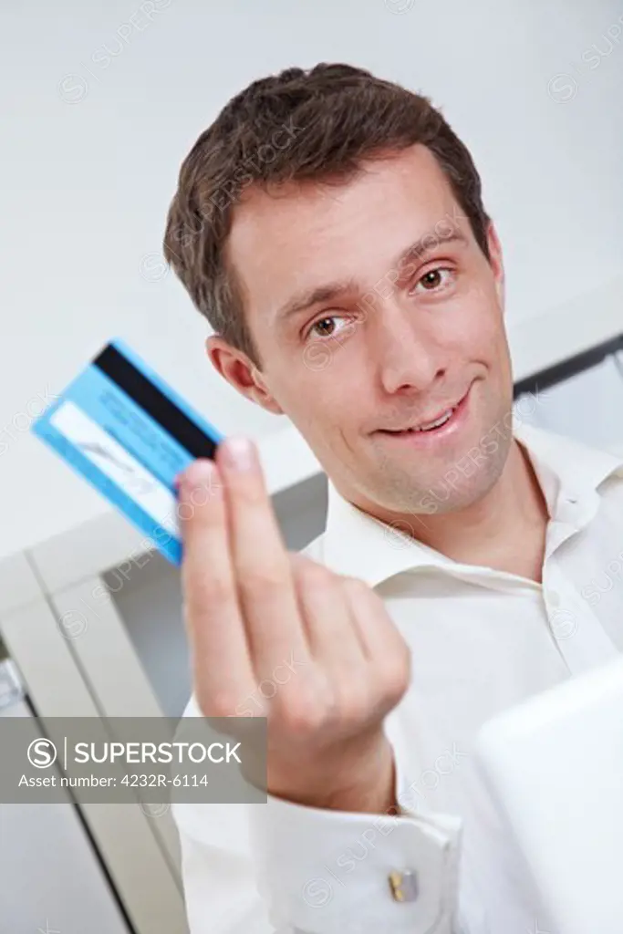 Business man on laptop showing credit card in his office