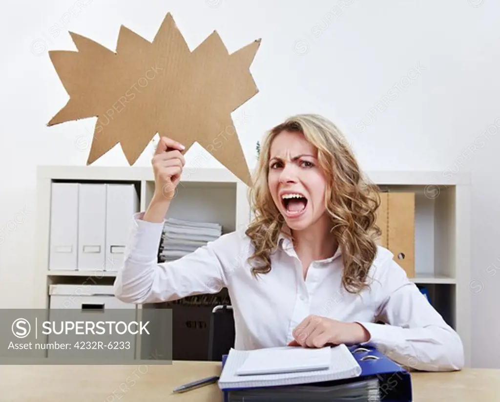 Angry woman sitting with empty jagged speech balloon in her office