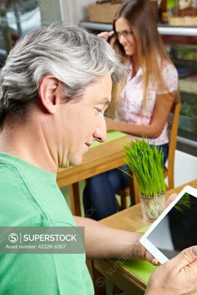 Elderly man in caf looking at his tablet computer