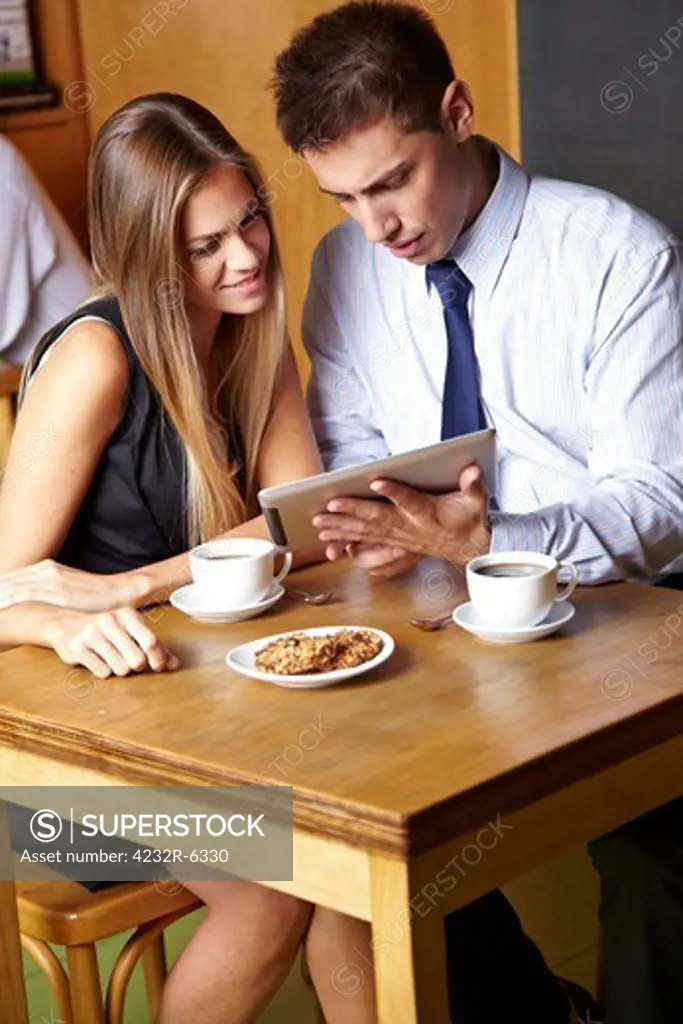 Two business people working with tablet computer in a caf