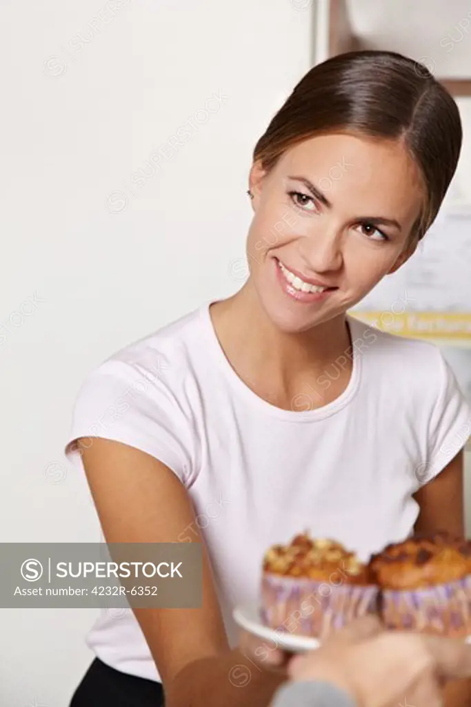 Happy smiling woman selling muffins in a caf