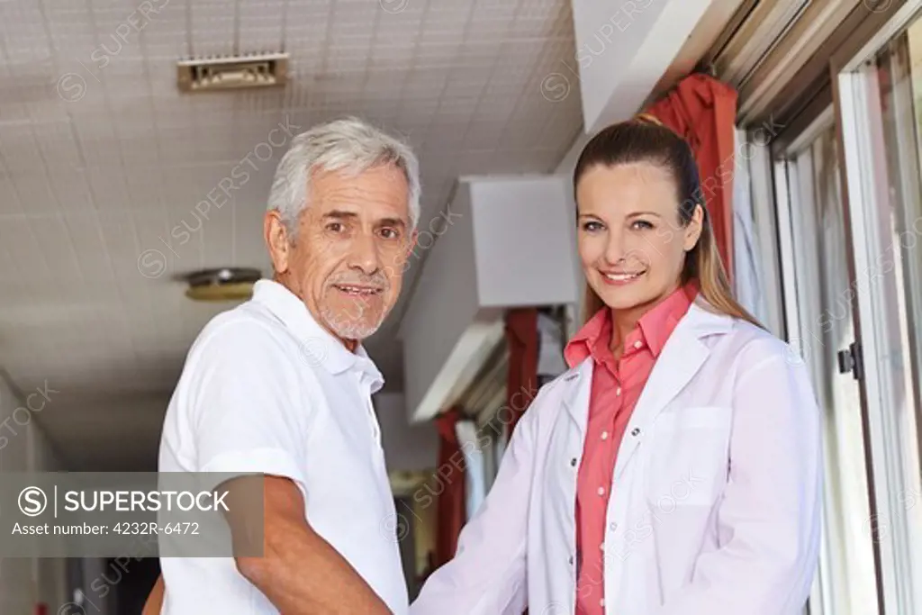 Senior man with nurse in floor of a hospital