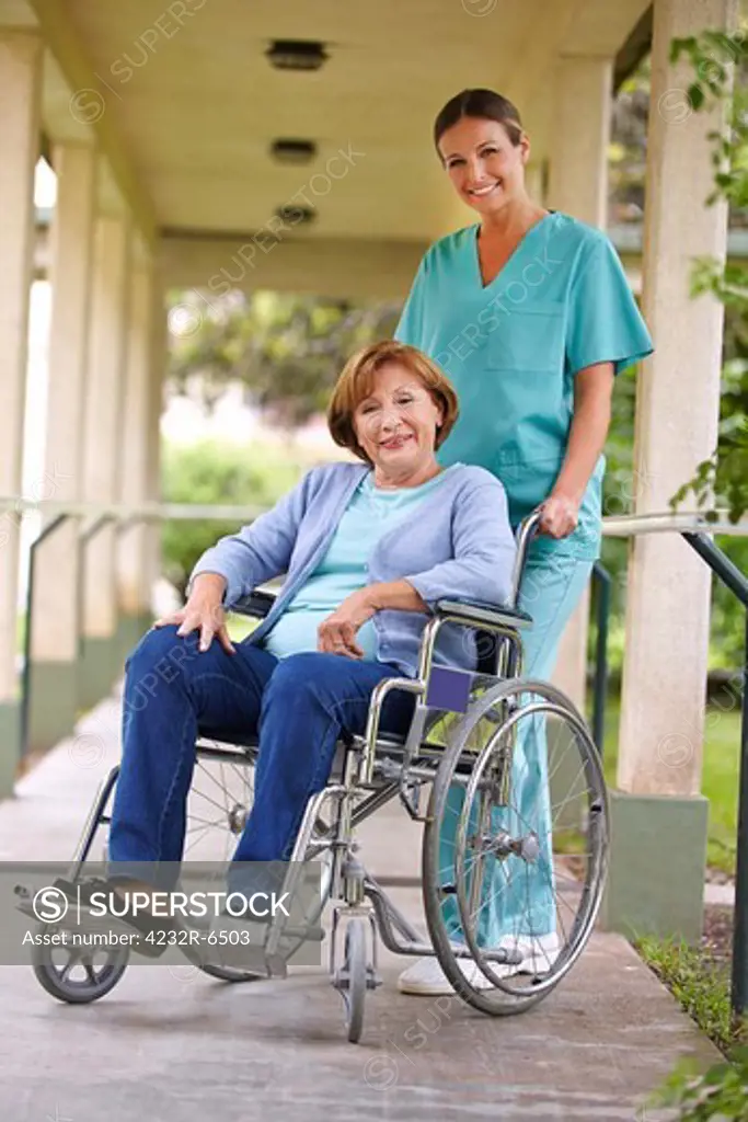 Senior woman in wheelchair with nurse in the garden of a nursing home