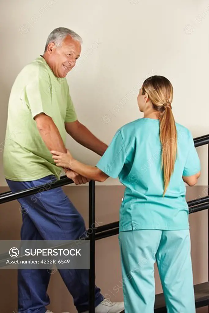Senior man on treadmill with physiotherapist holding railing