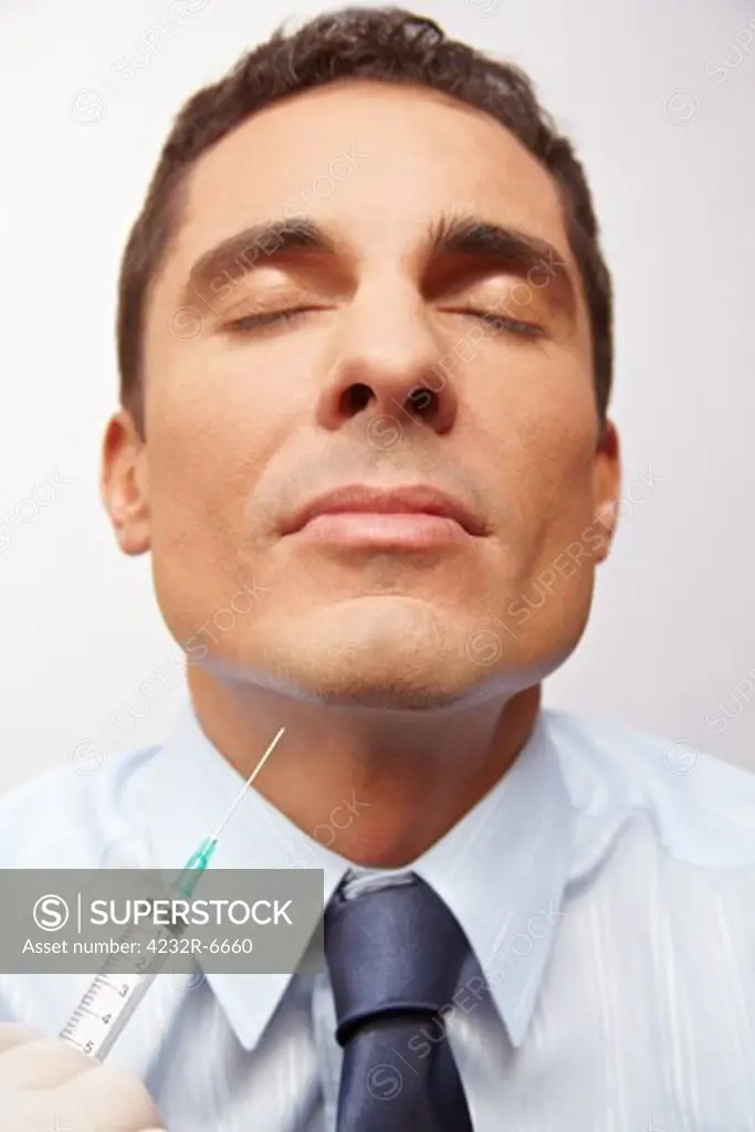 Business man getting needle in chin at cosmetic surgery