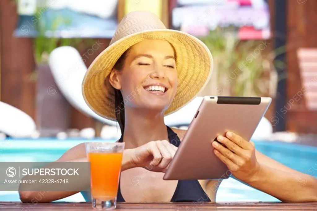 Happy smiling brunette woman with tablet computer in swimming pool