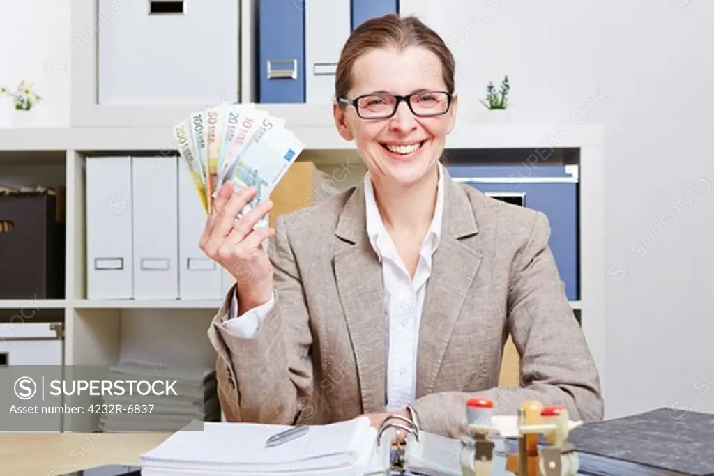 Smiling senior business woman in office with Euro money banknotes