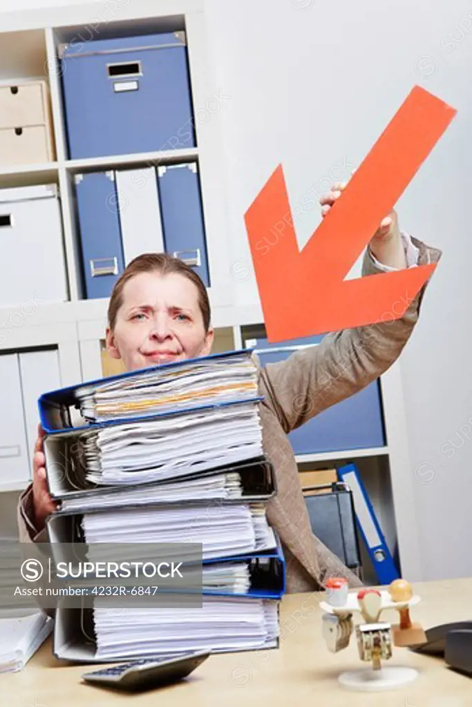 Stressed business woman pointing with arrow to stack of files