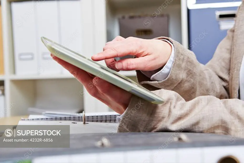 Finger of a business woman using touchscreen in tablet computer in her office