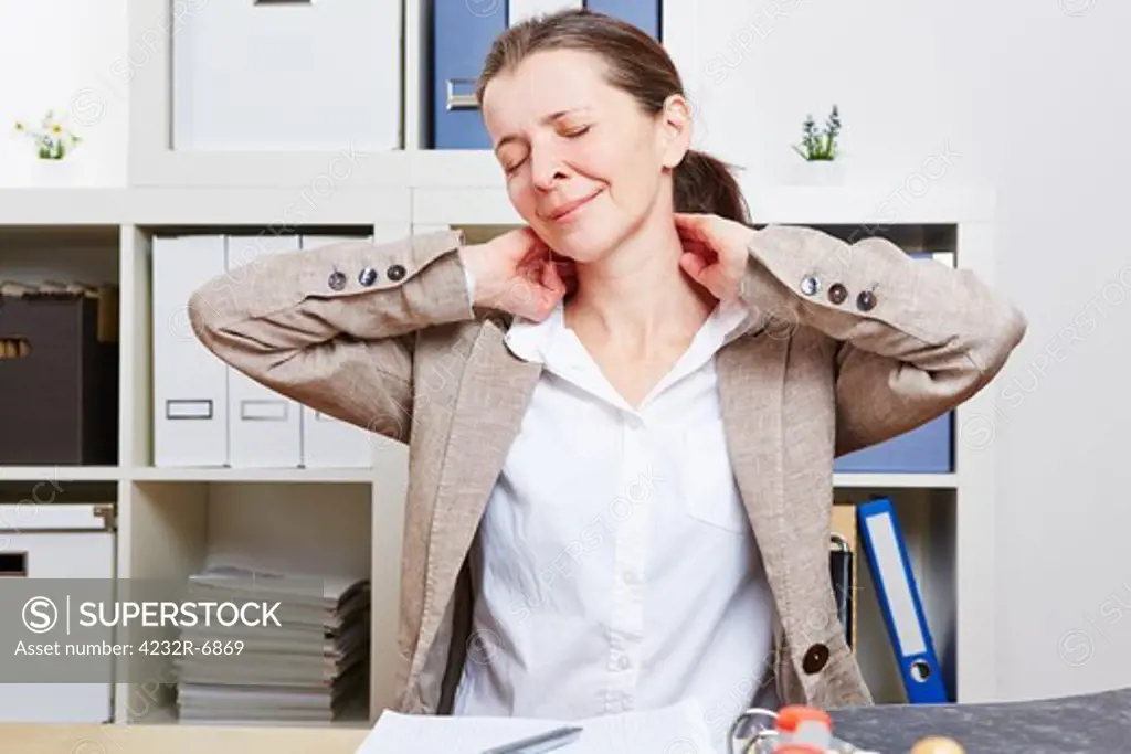 Senior business woman with pain massaging her neck in her office