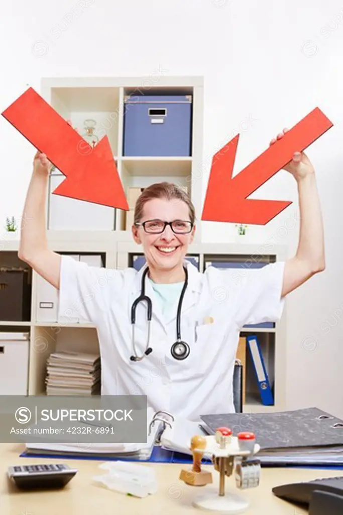 Happy female doctor pointing with red arrows to herself in her office